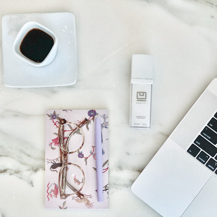 U Beauty Blog | Tips for Staying Sane While Staying Home | image of a cup of coffee, glasses and pen on a notebook, Ubeauty and a computer on a countertop