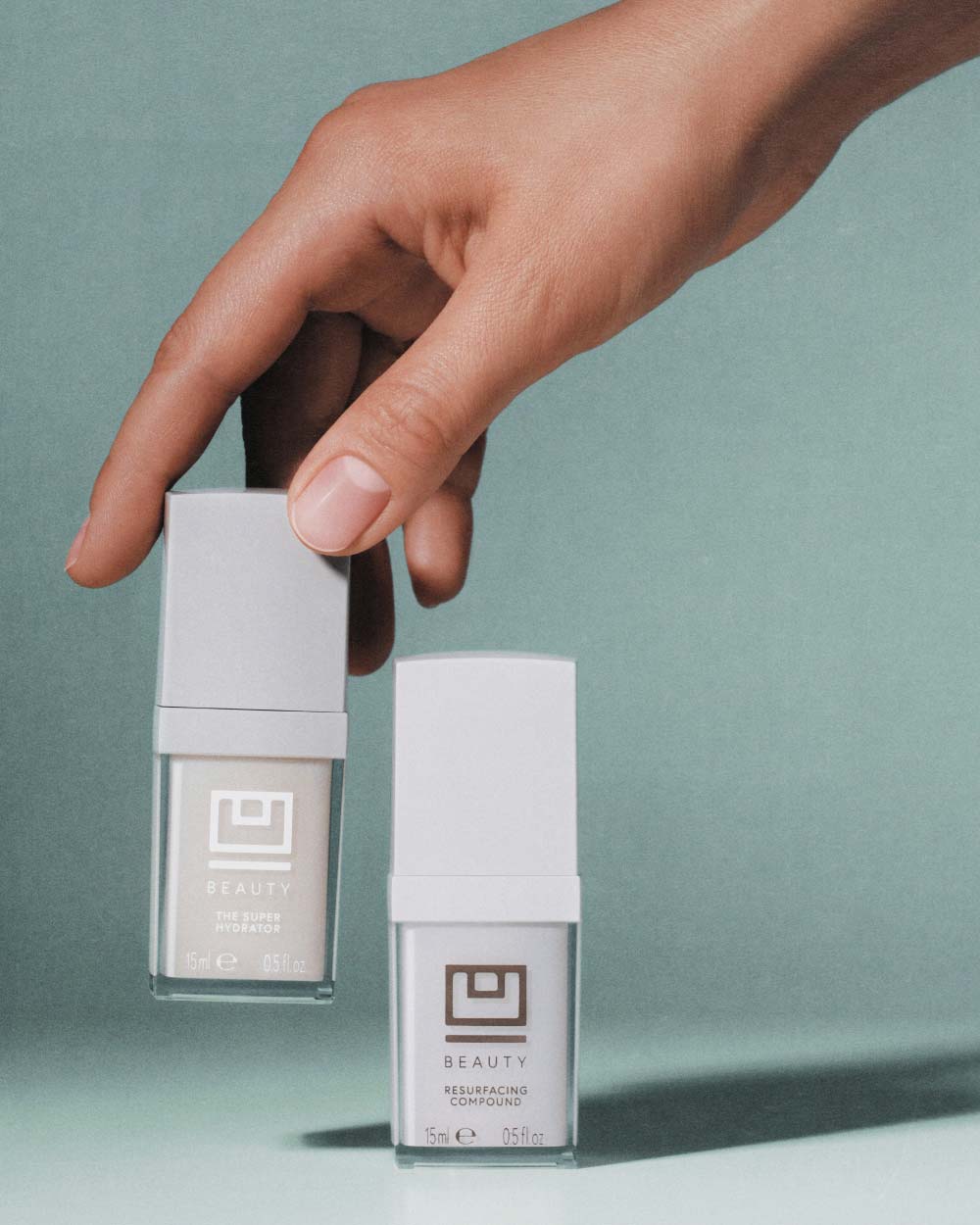 Una mano que sostiene dos botellas blancas con etiquetas 