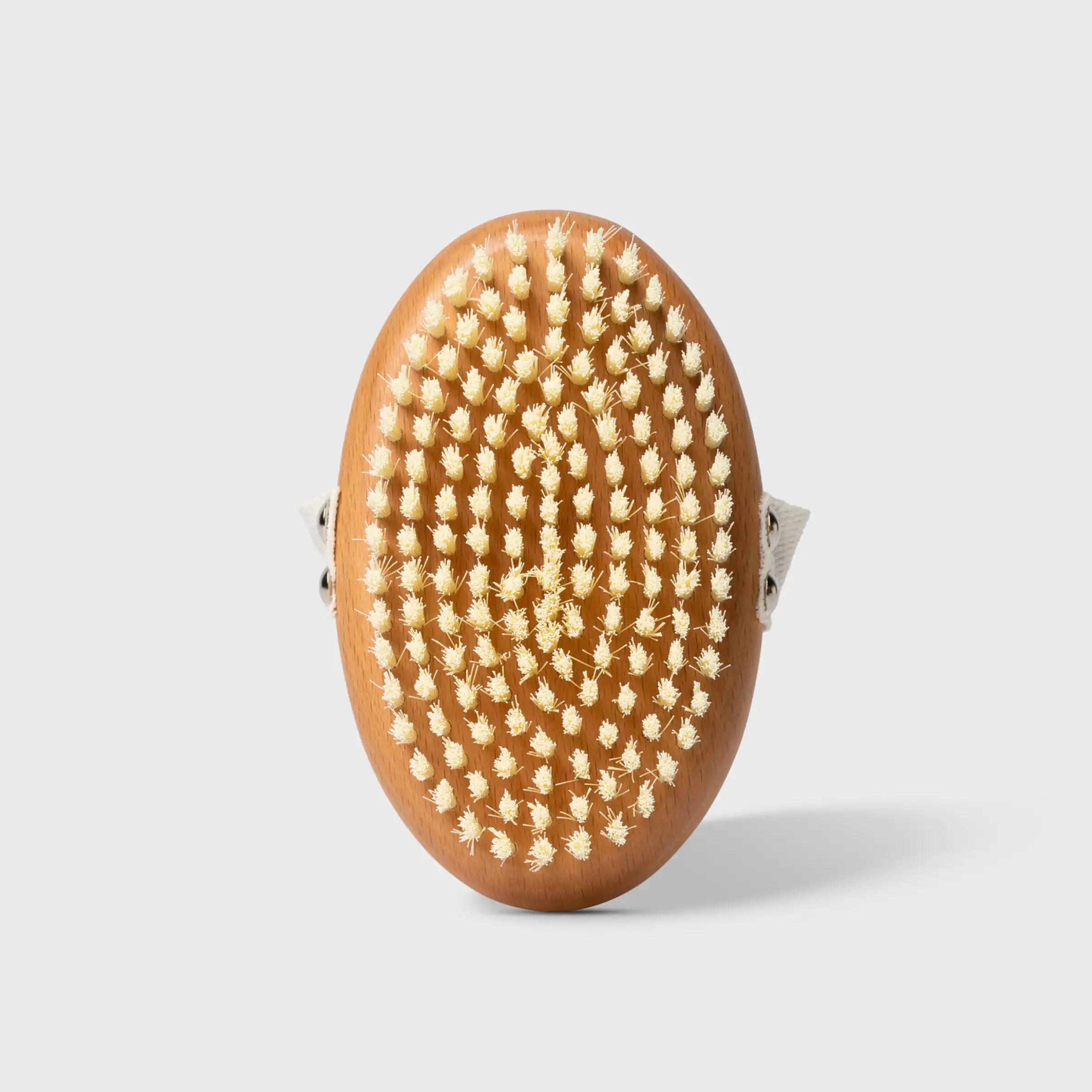 Wooden oval brush with densely packed natural bristles and fabric handle straps on sides.