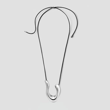 Collier en métal noir présentant un motif géométrique incurvé et, à son extrémité, un pendentif ovale de couleur argentée.
