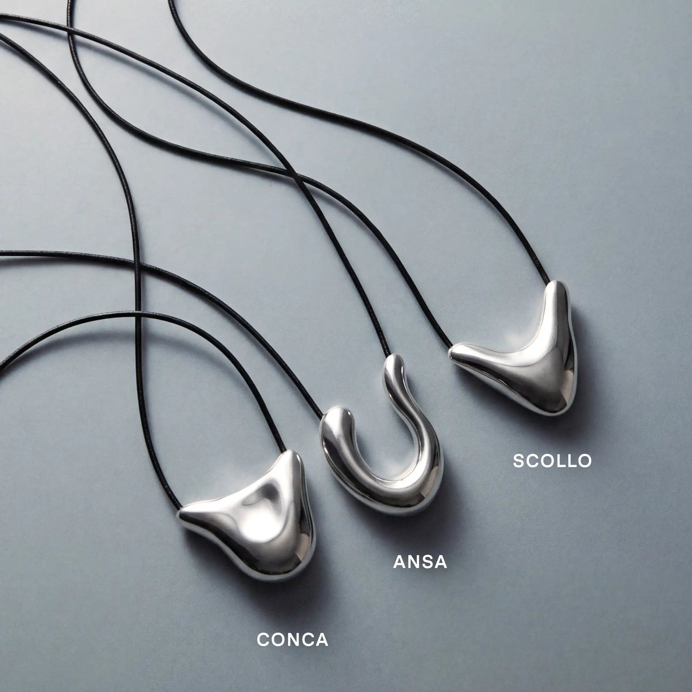 Trois colliers à pendentifs sculpturaux en argent aux formes incurvées, montés sur des cordons noirs, baptisés « Conca », « Ansa » et « Scollo ».
