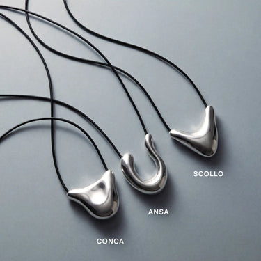 Trois colliers à pendentifs sculpturaux en argent aux formes incurvées, montés sur des cordons noirs, baptisés « Conca », « Ansa » et « Scollo ».