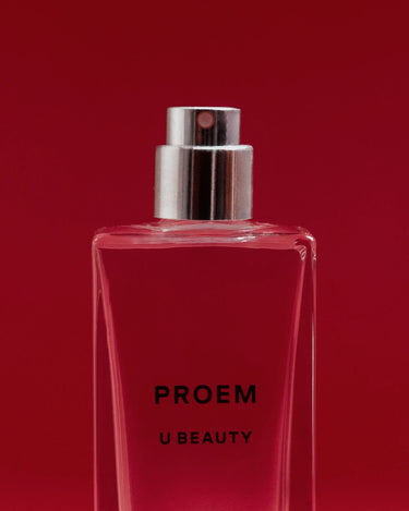 Red liquid in rectangular glass bottle with silver spray atomizer labeled "PROEM U BEAUTY" against red background.