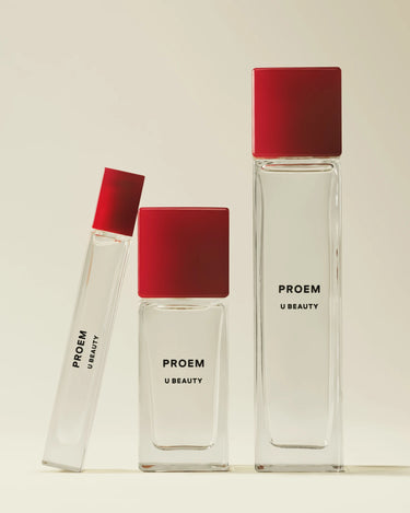 Trois flacons d'eau de parfum PROEM en verre transparent, dotés de bouchons rouges, de différentes tailles.