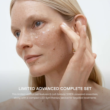Person applying skincare product to cheek with hand, showing facial texture and freckles.