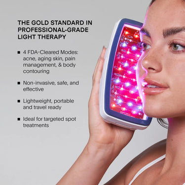 Person holding handheld Celluma LED device with red and pink lights against face.