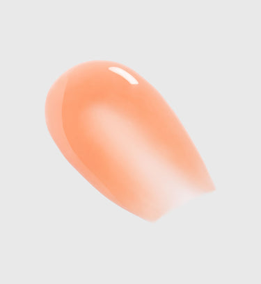 Peach-toned contour makeup product with smooth, rounded shape and glossy finish.